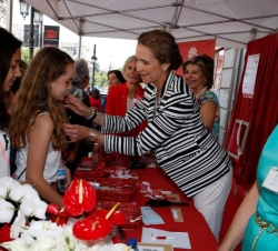Doña Elena coloca la insignia de Cáritas a unas niñas que habían hecho su donativo